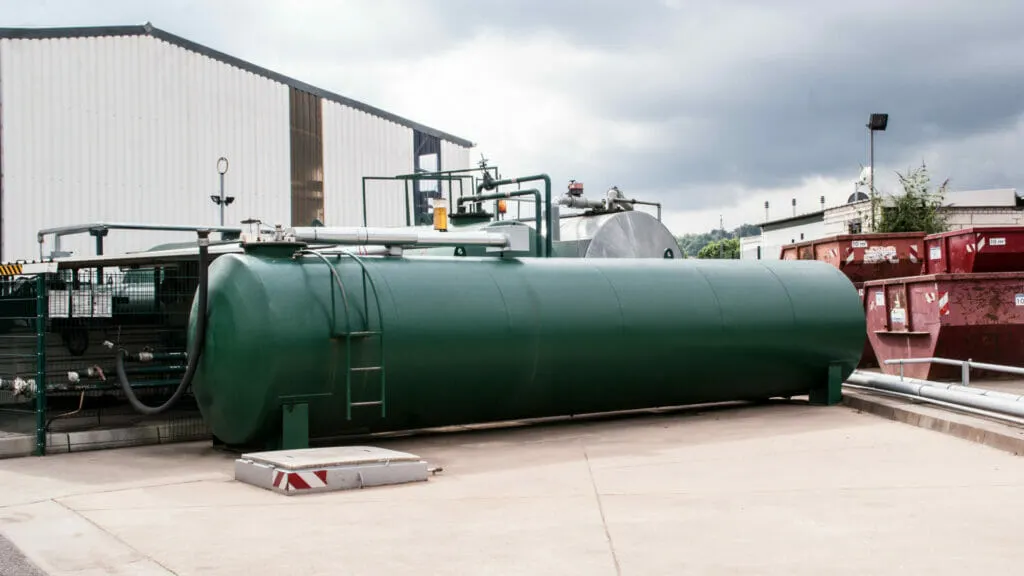 Grüner Öltank nach AwSV geprüft auf Betriebshof neben Halle