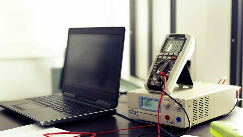 Arbeitsplatz eines Elektrotechnik Gutachters mit Laptop und elektronischen Messinstrumenten