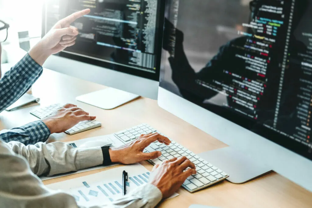 IT-Sachverständiger prüft den Code einer Software auf einem Bildschirm im Büro eines Kunden