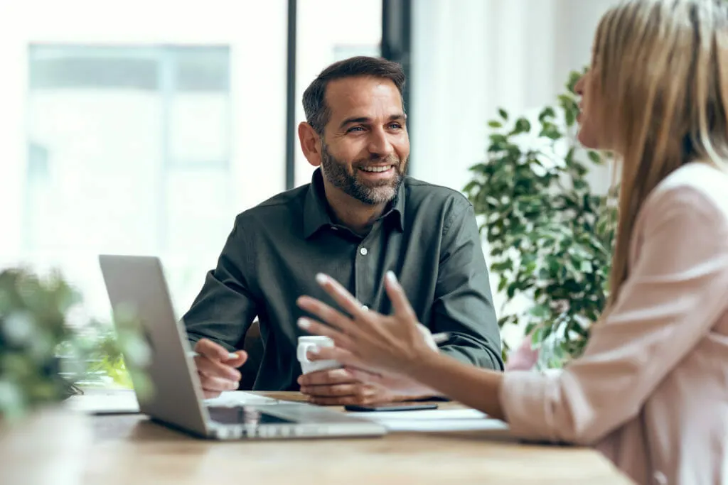 Sachverständiger und Kundin sitzen zusammen im Sachverständigenbüro und besprechen einen Schadensfall