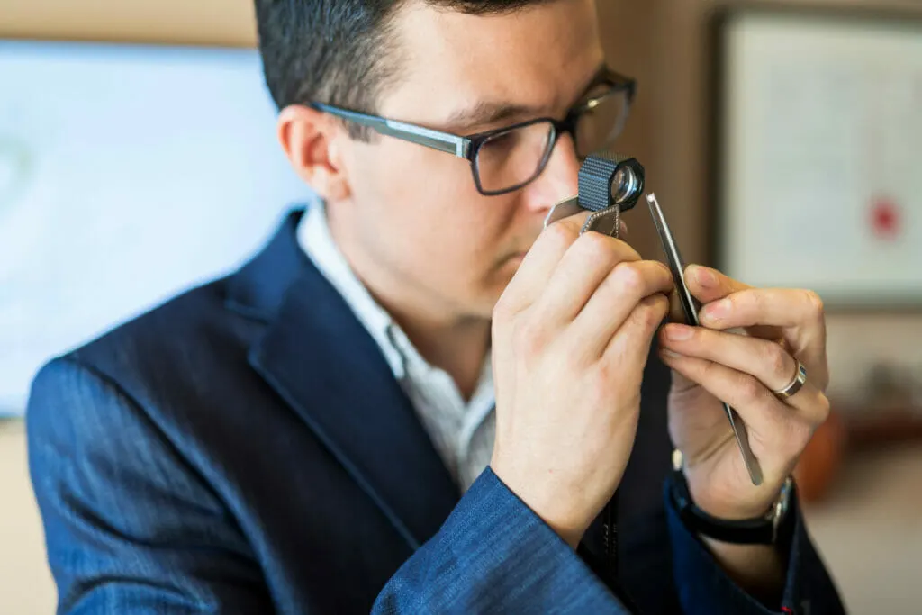 Sachverständiger für Wertgegenstände prüft mit Lupe Diamant auf Echtheit