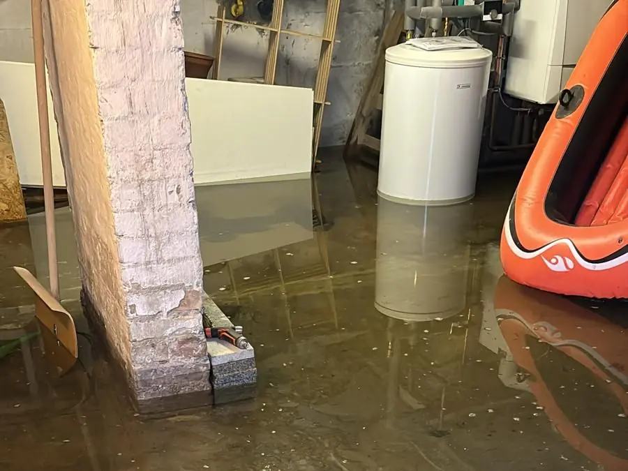 Kellerraum, dessen Boden großflächig unter Wasser steht, mit gemauertem Pfeiler und Warmwasserspeicher
