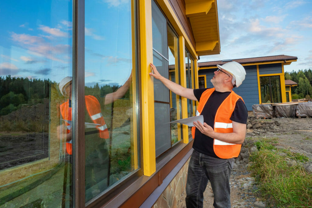 Sachverstaendiger Baugutachter ueberprueft ein Fenster auf einer Baustelle