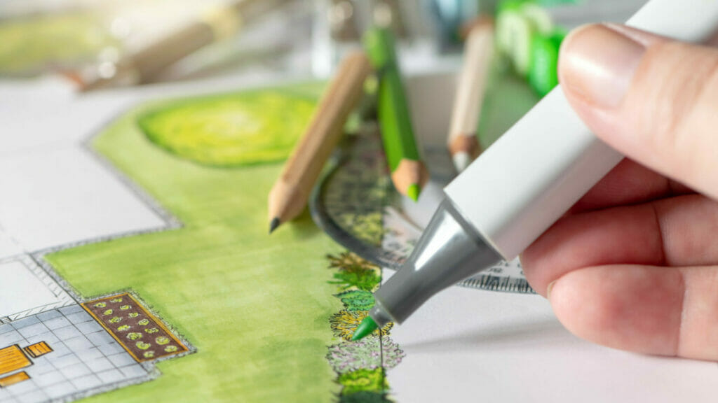 Sachverstaendiger für Garten- und Landschaftsbau zeichnet mit Stift einen farbigen Plan für einen Garten